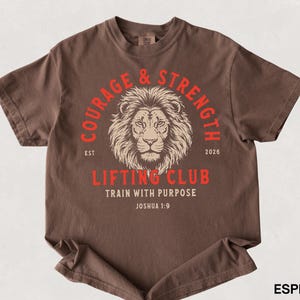 May include: Espresso-colored t-shirt with a lion graphic and the words "Courage & Strength Lifting Club" in red. The shirt also includes the text "Train with Purpose" and "Joshua 1:9".