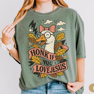 Trendy Silly Goose with a cute coquette bow and edgy lightening bolt design with a banner that says "honk if you love Jesus". Makes a great gift for Gen Z or Millennial Christians, Catholic friends or anyone looking for share the Gospel.
