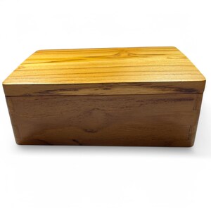 May include: A wooden box with a natural wood finish. The box has a hinged lid and is made of solid wood.