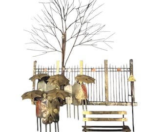 May include: Metal wall art depicting a park scene with figures holding umbrellas. The artwork features a tree, a fence, and a bench. The figures are in various colors, and the umbrellas are bronze.