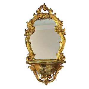 Vintage Syroco Wall Mirror from the Midcentury, Characterized by its Ornate Gold-toned Frame and Intergrated Shelf.