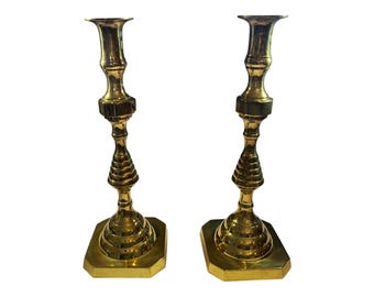 Puede incluir: Un par de candelabros de latón dorado con un diseño acanalado. Los candelabros tienen una base cuadrada y un tallo alto y delgado.