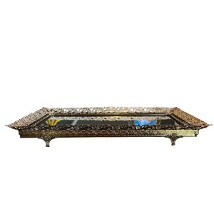Pode incluir: Uma bandeja retangular dourada e ornamentada com espelho e detalhes intrincados de filigrana nas bordas. A bandeja tem pequenos p&eacute;s decorativos e uma superf&iacute;cie reflexiva. O design &eacute; de inspira&ccedil;&atilde;o vintage.