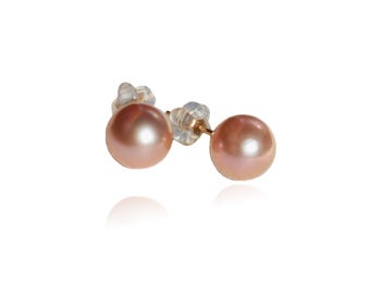 May include: A pair of pink pearl stud earrings. The pearls have a soft, lustrous sheen and are set on gold posts with clear plastic backings. The earrings are displayed against a white background.