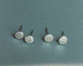 Könnte beinhalten: Vier silberne, gehämmerte Ohrstecker in Kreisform auf blauem Hintergrund. -AFRA JEWELRY STUDIO-