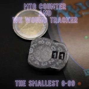 Può includere: Un piccolo contatore rotondo grigio con i numeri 11 stampati su di esso. Il contatore viene utilizzato per tenere traccia delle ferite o dei punti in un gioco. Il testo "The Smallest 0-99" è stampato sotto il contatore.