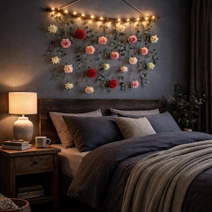 May include: A bedroom scene with a dark blue wall and a wooden headboard. A floral arrangement with roses and greenery hangs above the bed, illuminated by string lights. The bed is made with dark blue bedding and a gray blanket. A lamp and nightstand are on the left.
