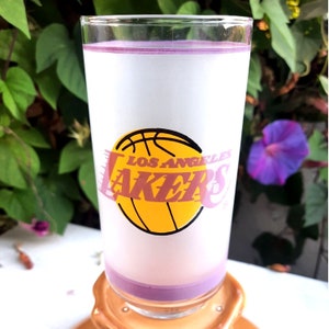 Peut inclure: Un verre givré contenant un liquide violet. Le verre est orné d'un logo des Los Angeles Lakers avec un ballon de basket et le texte "Los Angeles Lakers".