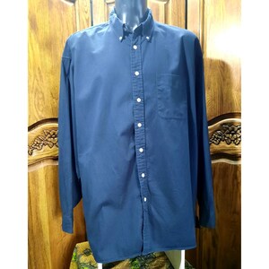 Op de afbeelding: Een marineblauw overhemd met lange mouwen en een button-down kraag. Het overhemd heeft een borstzak aan de linkerkant en witte knopen aan de voorkant. Het overhemd wordt op een mannequin getoond.