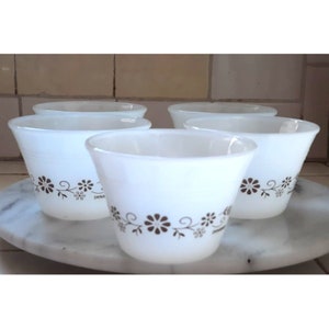 Puede incluir: Conjunto de cinco tazas de cerámica blanca para pudín con un diseño floral marrón. Las tazas están dispuestas en círculo sobre una superficie de mármol blanco.