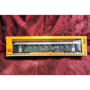 May include: A green model train car with the text "SBB CFF" on the side. The car is in a yellow box with the text "HO Fleischmann" on the bottom.