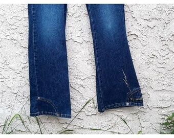 May include: A pair of dark blue denim jeans with a wide leg flare. The jeans have a classic five-pocket style and are made of a soft, comfortable denim.
