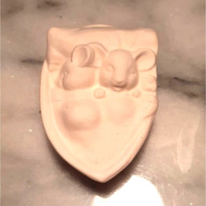 May include: White ceramic ornament featuring two mice nestled together. The ornament is shaped like a heart and has a smooth, matte finish.