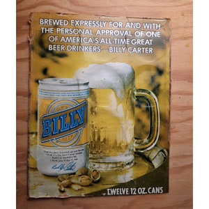 May include: A vintage advertisement for Billy Beer, featuring a can of beer and a glass mug filled with beer. The ad features a quote from Billy Carter, "I had this beer brewed up just for me. I think it's the best I ever tasted. And I've tasted a lot. I think you'll like it, too." The ad also states that the beer is brewed expressly for and with the personal approval of one of America's all-time great beer drinkers. The ad is for a 12-ounce can of beer.