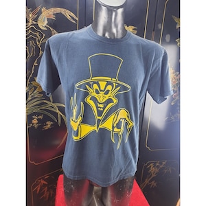 Pode incluir: Uma camiseta azul escura com um gráfico amarelo de um personagem de desenho animado usando um chapéu de cartola e um sorriso travesso.