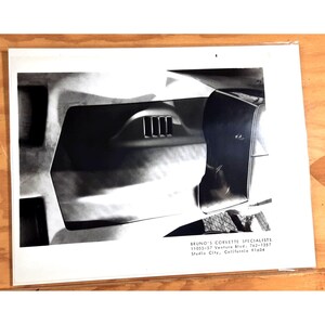 May include: Black and white photograph of a classic car's rear fender with a chrome accent and a small vent. The photo is from Bruno's Corvette Specialists, 11055-57 Ventura Blvd., 762-1357, Studio City, California 91604.