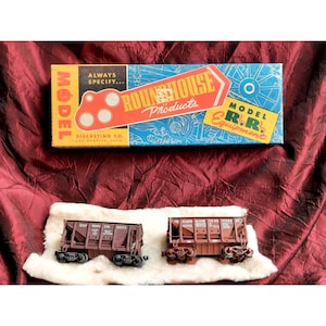 May include: Two brown model railroad hopper cars. The car on the left is labeled "Great North ERM 88373". The car on the right is labeled "Chicago & North Western Ry 12333". The cars are sitting on a white surface. The cars are in a box labeled "Roundhouse Products Model R.R. Equipment".