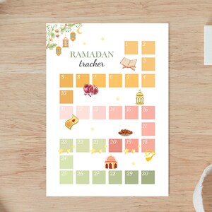 May include: A printable Ramadan tracker with a floral design and illustrations of lanterns, pomegranates, dates, and a mosque. The tracker has 30 boxes for each day of Ramadan.