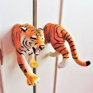 May include: A pair of orange and black tiger figurine drawer pulls. The tigers are in a crouching position with their mouths open.