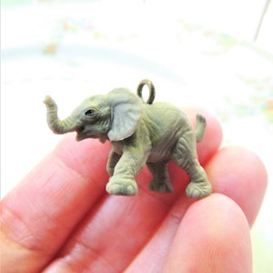 May include: A small gray plastic elephant charm with a loop for hanging. The elephant has a textured surface and a raised trunk.