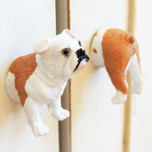 May include: Two white and brown bulldog figurines with black noses. The bulldog on the left is standing on its hind legs with its front paws raised. The bulldog on the right is standing on its hind legs with its front paws raised and its tail curled.