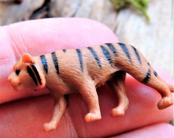 May include: A small, brown and black plastic tiger figurine. The tiger is walking with its head turned to the left.