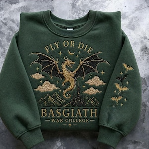 Puede incluir: Sudadera verde oscuro con dise&ntilde;o de drag&oacute;n bordado. El dise&ntilde;o incluye un drag&oacute;n dorado, nubes, un castillo y el texto "FLY OR DIE" y "BASGIATH WAR COLLEGE". Las mangas presentan murci&eacute;lagos bordados.