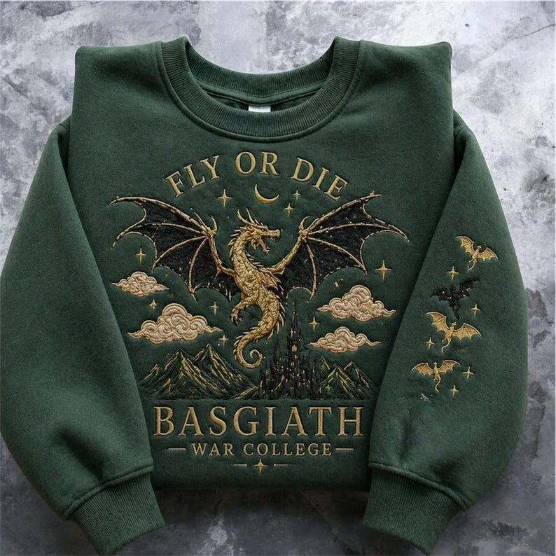 Puede incluir: Sudadera verde oscuro con dise&ntilde;o de drag&oacute;n bordado. El dise&ntilde;o incluye un drag&oacute;n dorado, nubes, un castillo y el texto "FLY OR DIE" y "BASGIATH WAR COLLEGE". Las mangas presentan murci&eacute;lagos bordados.