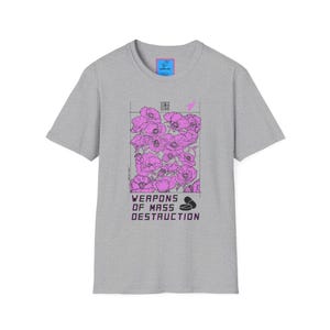 May include: A gray t-shirt featuring a graphic of pink flowers with the text "WEAPONS OF MASS DESTRUCTION". The design is in a rectangular frame with a small pink bird and other graphic elements.