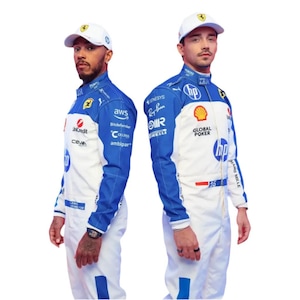 Puede incluir: Dos personas vestidas con trajes de carreras blancos y azules y gorras blancas con el logo de Ferrari. Los trajes tienen logotipos de patrocinadores y el número 16. El fondo es blanco liso.