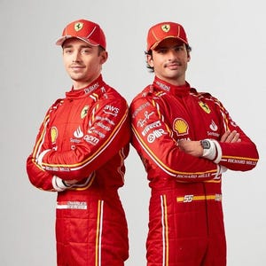 K&ouml;nnte beinhalten: Zwei Rennfahrer in roten Rennanz&uuml;gen mit gelben und wei&szlig;en Akzenten. Die Anz&uuml;ge haben verschiedene Logos und Sponsoren aufgedruckt. Die Fahrer tragen rote Baseballkappen mit dem Ferrari-Logo.