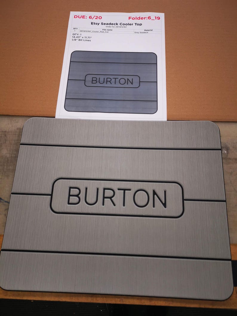 May include: A gray, rectangular, non-slip surface with the word "BURTON" printed in black. The surface is 14.43 inches by 11.71 inches and has 1/8 inch bit lines.