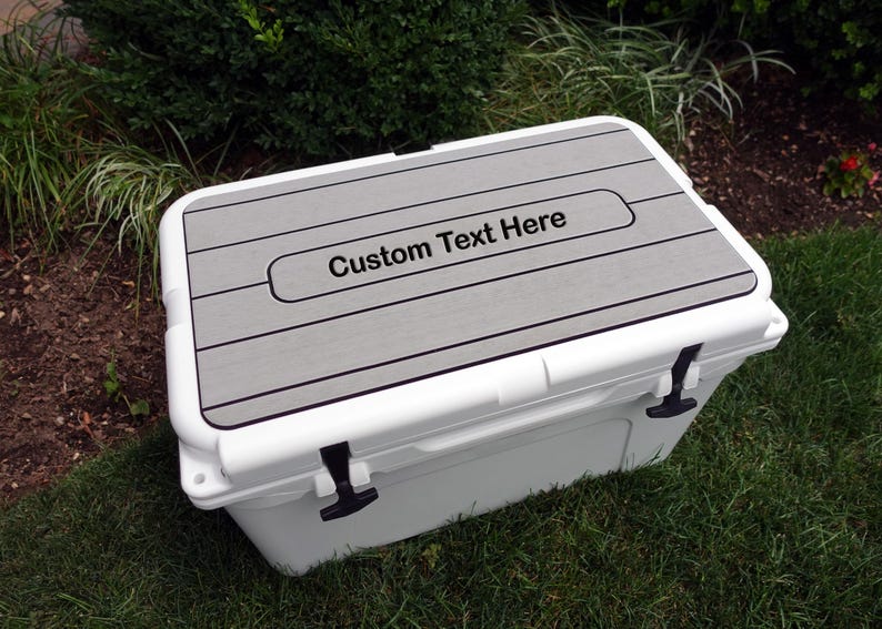 May include: White cooler with a gray, wood-look lid. The lid has a rectangular cutout with the text "Custom Text Here" in black.