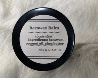 May include: A black-lidded jar of unscented beeswax balm. The label reads "Beeswax Balm" and lists ingredients: beeswax, coconut oil, and shea butter. The net weight is 28g.