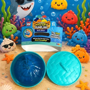 May include: A "Crazy Fun" Shark Edition "Mystery Dumpling" toy set with a shark wearing sunglasses, colorful dumpling toys, and a blue container. The packaging reads "Will You Find The Super Rare Shark Dumpling?" and "The Viral Mystery Dumpling!"