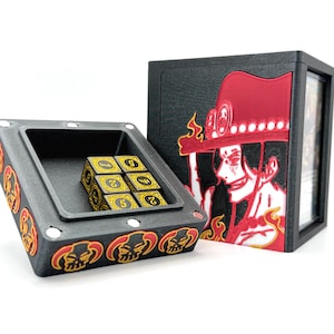 May include: Black and red card game storage box and dice tray. The box features a red and black graphic of a character with a hat. The dice tray contains six gold and black dice. The tray and box have a skull design.
