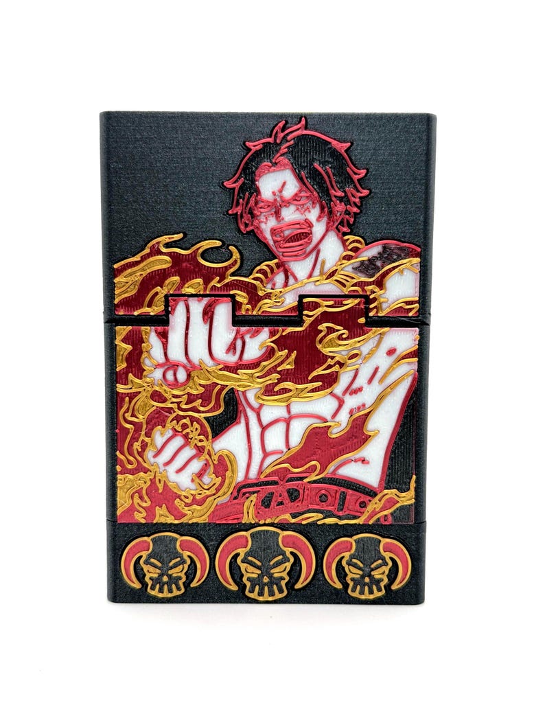 May include: Black rectangular case featuring a red, white, and gold illustration of a character with flames. The case has three skull designs at the bottom. The character is depicted with an open mouth and intense expression.