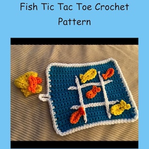 Puede incluir: Un juego de tres en raya de peces tejido a ganchillo. El tablero es un cuadrado de hilo azul con un borde blanco y una cuadrícula de tres en raya blanca. Las piezas del juego son peces amarillos y naranjas. El texto "Fish Tic Tac Toe Crochet Pattern" está en la parte superior.