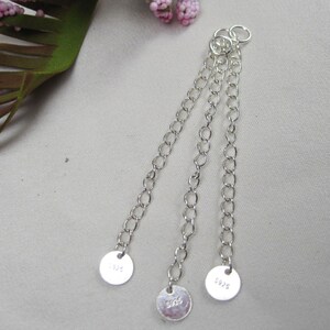 May include: Three silver chains with round silver tags at the end. The tags are stamped with the numbers "5925", "5925", and "5925".