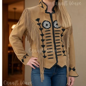 May include: A tan jacket featuring long fringe detailing on the shoulders and chest. The garment includes black trim, decorative black horizontal bars, and floral embroidery on the front. The jacket has long sleeves and a high collar design.