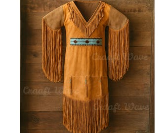 May include: A tan suede dress featuring long fringe detailing on the sleeves and hem, a V-neckline with fringe trim, and a horizontal band across the midsection with a blue and brown geometric pattern, accented by small turquoise-colored beads.