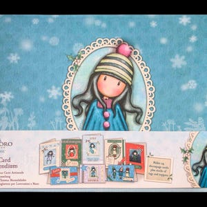 May include: Craft card compendium featuring a whimsical illustration of a girl in a winter hat and coat. The set includes various craft cards with decorative designs and the text "SANTORO LONDON gorjuss Craft Card Compendium".