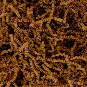 May include: A dense collection of brown crinkle-cut paper shreds. The individual strips of paper are folded into a zigzag pattern, creating a textured, layered appearance that fills the entire frame with a consistent earthy brown color tone.