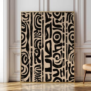 Puede incluir: Una impresión de arte mural rectangular con fondo beige y un patrón repetitivo de formas abstractas negras dibujadas a mano, que incluyen líneas verticales gruesas, trazos curvos y motivos circulares, todo dentro de un marco fino de color dorado.