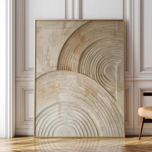 Op de afbeelding: Een rechthoekig wandkunstwerk met een getextureerd, beige oppervlak met uitgesneden, concentrische cirkelpatronen. Het kunstwerk is ingelijst in een dunne, goudkleurige metalen lijst en toont een gelaagd ontwerp in reliëfstijl.