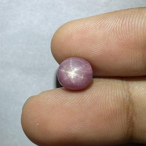 May include: A pink star ruby cabochon gemstone with a six-rayed star.