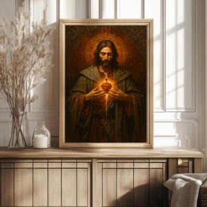 Puede incluir: Un retrato religioso enmarcado representa una figura con pelo largo y barba, sosteniendo un coraz&oacute;n brillante. La obra de arte presenta tonos c&aacute;lidos de marr&oacute;n, dorado y rojo, con un efecto de halo alrededor de la cabeza. La pintura se exhibe en un mueble de madera.