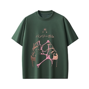 Pu&ograve; includere: T-shirt verde scuro con girocollo. La parte anteriore presenta un design grafico di mani che tengono una sostanza rosa e appiccicosa, con testo giapponese sopra. Un disegno a stella e goccia &egrave; sopra il testo.