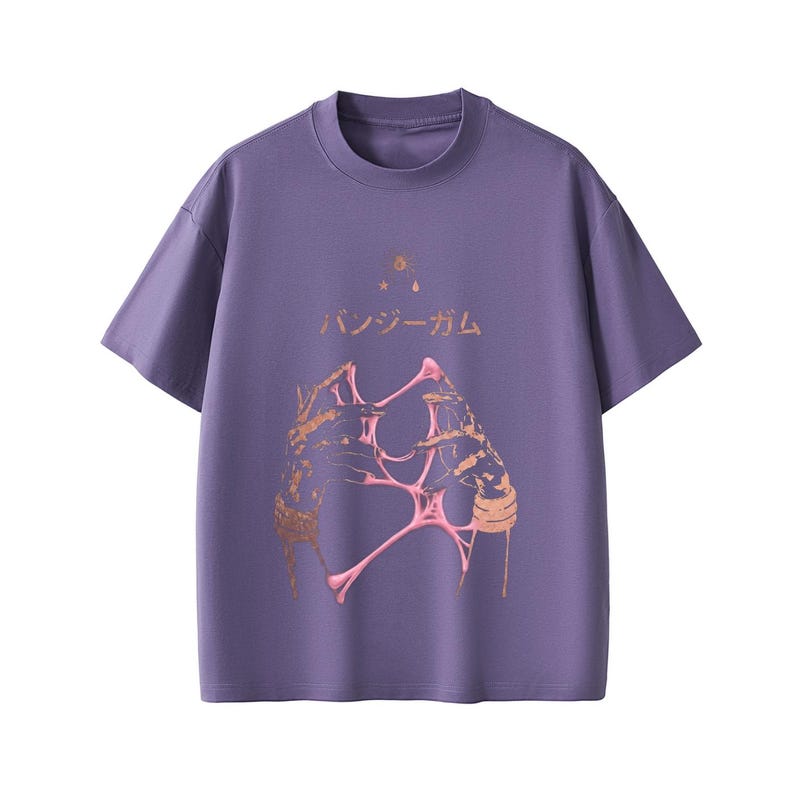 Pu&ograve; includere: T-shirt viola a maniche corte con scollo tondo. Il davanti presenta un design grafico con elementi dorati e rosa e testo giapponese. La maglietta ha una vestibilit&agrave; ampia.