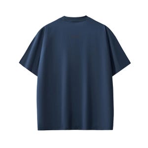 Pu&ograve; includere: Una maglietta blu navy a maniche corte. La maglietta ha un girocollo e una vestibilit&agrave; rilassata. Il tessuto sembra essere di un colore solido e morbido. Il retro della maglietta &egrave; visibile, mostrando il design semplice.